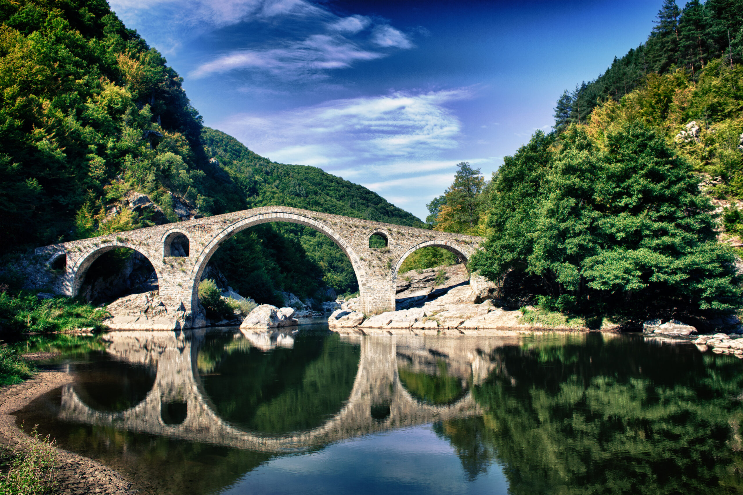 Arched bridge on river that connects the mountains with the lower land.